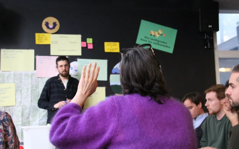 Une participante lève la main lors d'un atelier collectif sur le projet des microparlements.