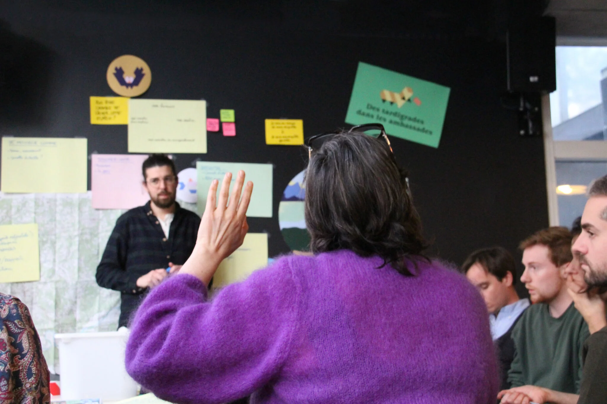 Une participante lève la main lors d'un atelier collectif sur le projet des microparlements.
